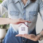 midsection-of-woman-protecting-house-model-at-office